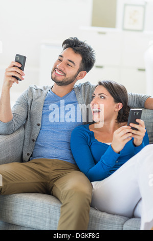 Couple relaxing on sofa with cell phones Banque D'Images