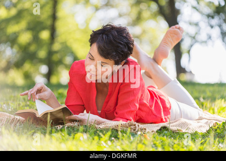 Young woman lying on grass and reading book Banque D'Images