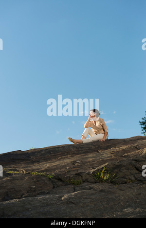 Mature Woman sitting on rock Banque D'Images