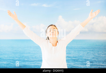 Portrait de femme aux bras levés en face de toile avec de la mer et du ciel Banque D'Images