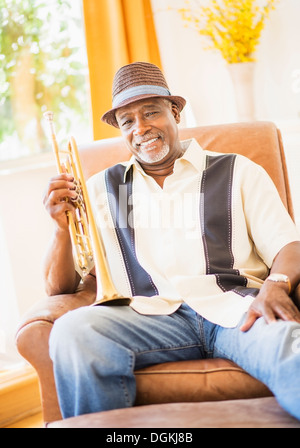 Portrait de l'homme assis dans un fauteuil et holding trumpet Banque D'Images