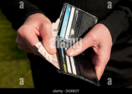 Un homme tenant un porte-monnaie et billets de dix livres. Banque D'Images