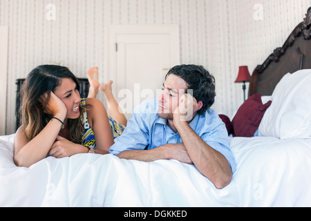 Jeune couple lying on bad in hotel room Banque D'Images