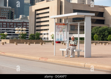 États-unis, Texas, Dallas, Senior man sitting at bus stop et de messagerie texte Banque D'Images