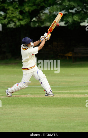 Un cricketer dans des vêtements de protection complets, conduire la boule vers l'observateur. Banque D'Images