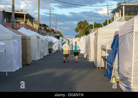 Un homme et femme couple marche dans une rue vide fermé entre les étals des vendeurs de rue se dresse des tentes. Banque D'Images