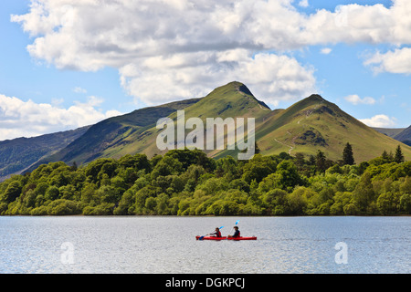 Deux personnes un paddle red canoe sur Derwent Water avec Catbells en arrière-plan. Banque D'Images