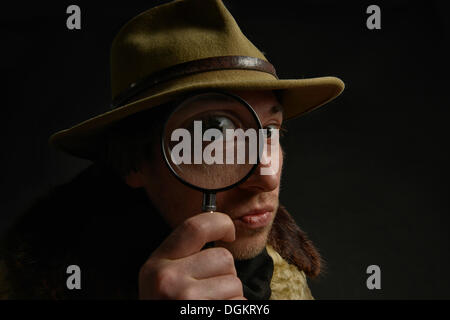 Man holding magnifying glass en face de son oeil, Suisse Banque D'Images