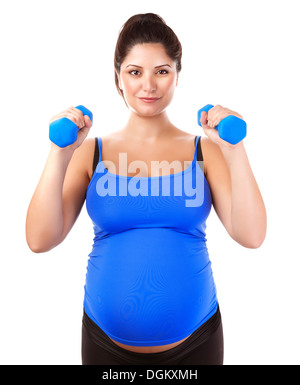 Fille enceinte sportive haltères levage isolé sur fond blanc, à l'intérieur d'entraînement, le sport pour femme enceinte femme Banque D'Images