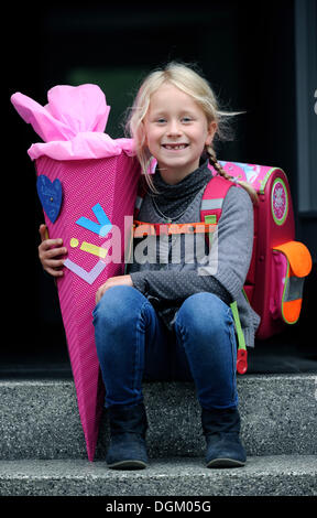 Fille, 6 ans, avec sac à dos pour l'école et de l'école traite avec cône pour la première journée d'école Banque D'Images