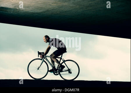 Cyclist voyageant sous un pont Banque D'Images