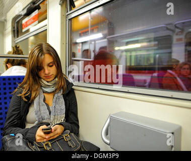 Jeune femme écrivant SMS pendant un voyage en train de banlieue, Stuttgart, Bade-Wurtemberg Banque D'Images