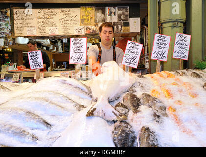 Poissonnier avec des fruits de mer sur glace, Marché public de Pike Place, le marché aux poissons, Seattle, Washington, USA Banque D'Images