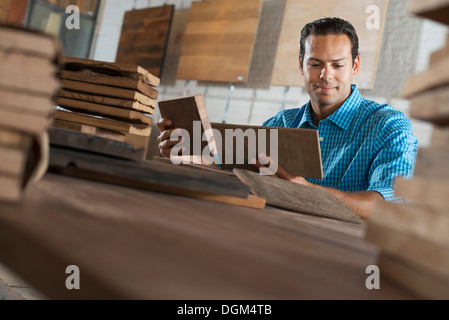 Un jeune homme dans un atelier. L'examen d'un échantillon de bois récupérés. Banque D'Images