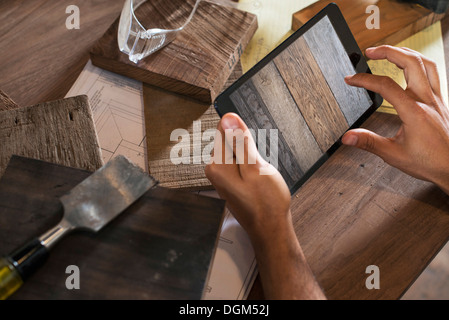 Un jeune homme dans un atelier. À l'aide d'une tablette numérique à tenir des registres et photographier des objets. Banque D'Images
