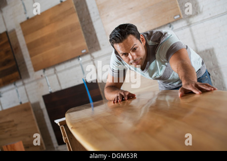 Un jeune homme dans un atelier avec stock de bois recyclées et régénérées. Banque D'Images