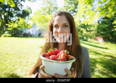 À la ferme. Une femme portant un bol de fraises cueillies. Banque D'Images