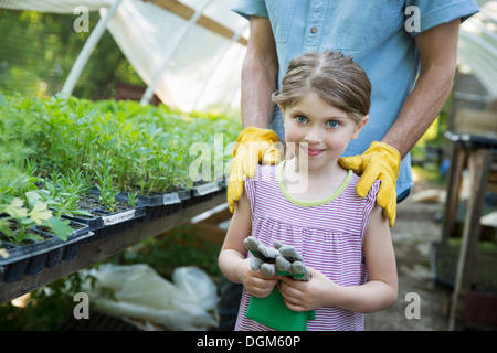 Ferme sur les enfants Les adultes travaillent ensemble gants de jardinage enfant jeune homme debout à côté de banc de jeunes semis dans Banque D'Images