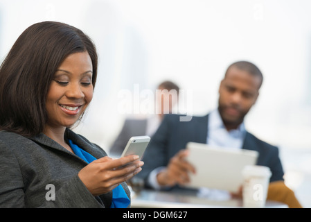 L'été. Une femme à l'aide de son téléphone intelligent, et un homme à l'aide d'une tablette numérique. Banque D'Images