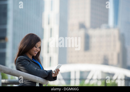 L'été. Une femme dans un costume gris à l'aide d'un téléphone intelligent. Banque D'Images