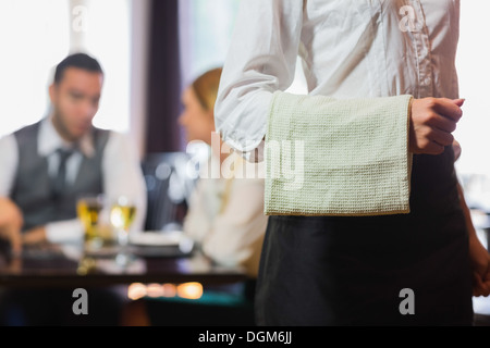 Waitress standing in front of two business people talking Banque D'Images