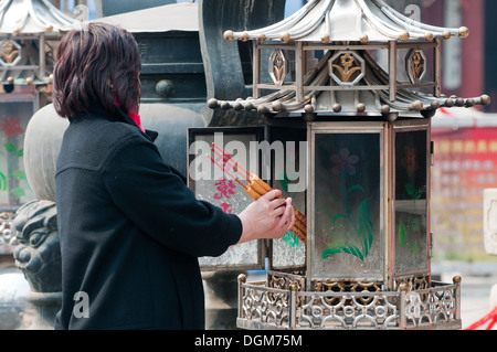 Femme priant devant d'encens dans le Temple Dongyue taoist dans le district de Chaoyang, Beijing, Chine Banque D'Images