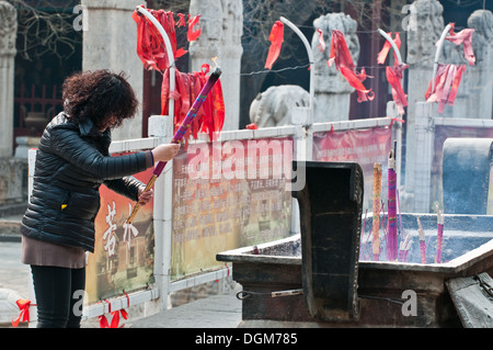 Femme priant devant d'encens dans le Temple Dongyue taoist dans le district de Chaoyang, Beijing, Chine Banque D'Images