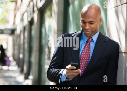 Les gens d'affaires. Un homme en costume et cravate rouge, contrôler son téléphone. Banque D'Images