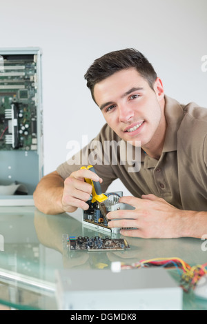 Handsome smiling computer engineer repairing hardware avec une pince Banque D'Images