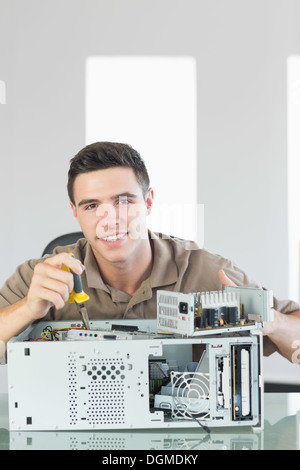 Handsome smiling computer engineer repairing open computer Banque D'Images