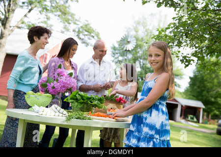 Partie de la famille des salades fruits légumes table parents enfants. Deux filles, une jeune femme d'âge mûr Banque D'Images