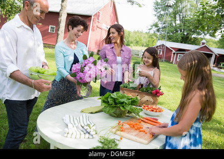 Partie de la famille. Une table dressée avec des salades et des fruits et légumes frais. Les parents et les enfants. Banque D'Images