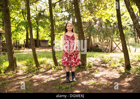 Une fille dans une robe d'été debout dans un bosquet d'arbres. Banque D'Images