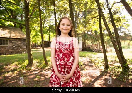 Une fille dans une robe d'été debout dans un bosquet d'arbres. Banque D'Images