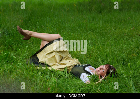 Jeune femme dans un dirndl avec une couronne de houblon, allongé dans l'herbe, Hop de Vicequeen Hollerdau ou Holledau Hallertau, Bavaria, Banque D'Images