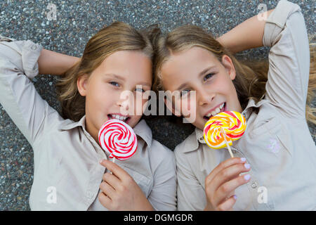 Les filles, 9 lits jumeaux, gisant sur le sol avec des sucettes colorées Banque D'Images