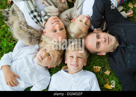 Famille avec trois enfants allongés sur l'herbe Banque D'Images