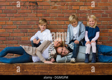 Portrait de famille avec trois enfants, les parents sont couchés, les enfants sont assis sur eux Banque D'Images