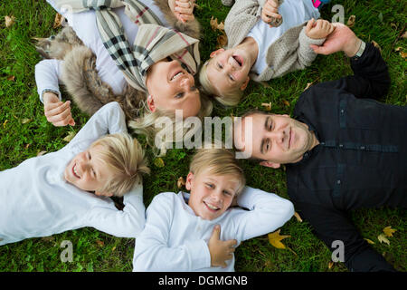 Famille avec trois enfants allongés sur l'herbe Banque D'Images