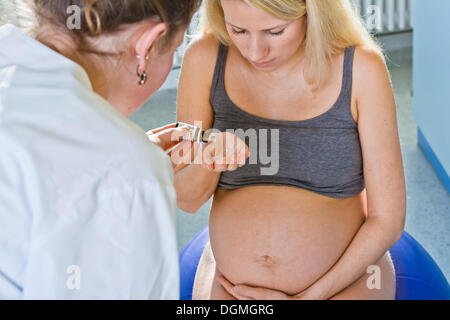 Pregnant woman recieving médicament homéopathique de la sage-femme lors de l'accouchement, Allemagne Banque D'Images