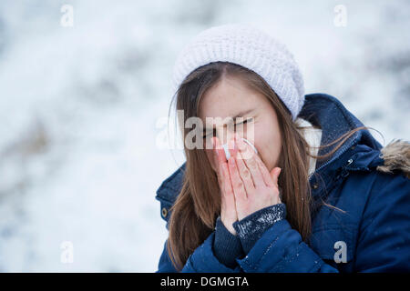 Jeune femme portant des vêtements d'hiver s'être mouché le nez, Allemagne Banque D'Images