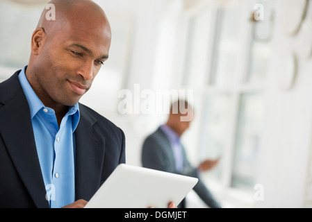 Les gens d'affaires. Un homme dans un costume d'affaires à l'aide d'une tablette numérique. Banque D'Images