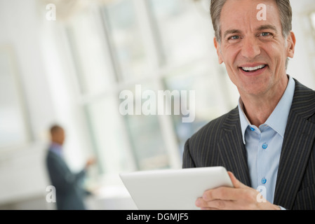 Les gens d'affaires. Un homme en costume à l'aide d'une tablette numérique. Banque D'Images