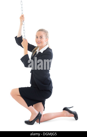 Content young businesswoman à genoux sur le sol en tirant une chaîne Banque D'Images
