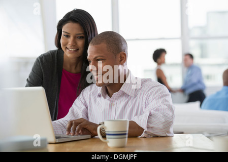 Office de tourisme. Deux personnes, un homme et une femme, le partage d'un ordinateur portable. Banque D'Images