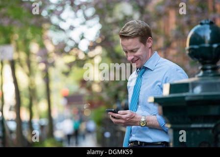 Un homme en chemise et cravate, d'affaires à la recherche et le contrôle de son téléphone. Banque D'Images