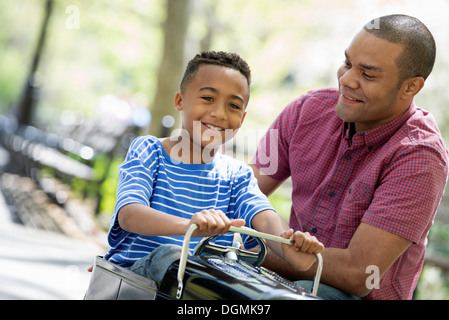 Un garçon équitation une ancienne voiture jouet Peddle. Banque D'Images