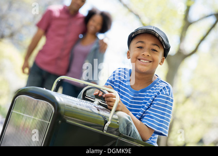 Un garçon équitation une ancienne voiture jouet Peddle. Banque D'Images