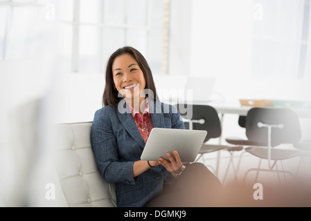 L'entreprise. Une femme assise à l'aide d'une tablette numérique. Banque D'Images