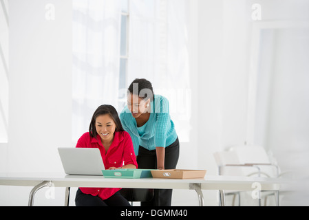 L'entreprise. Deux femmes se penche au-dessus et en utilisant un ordinateur portable. Banque D'Images